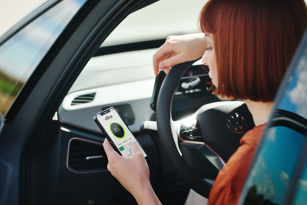 Frau sitzt in einem Auto und bedient die neue ELINX-App. 